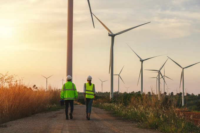 Two workers walking under wind turbines