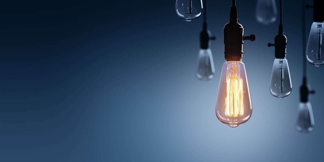 Insights Light bulbs hanging in front of a blue backdrop