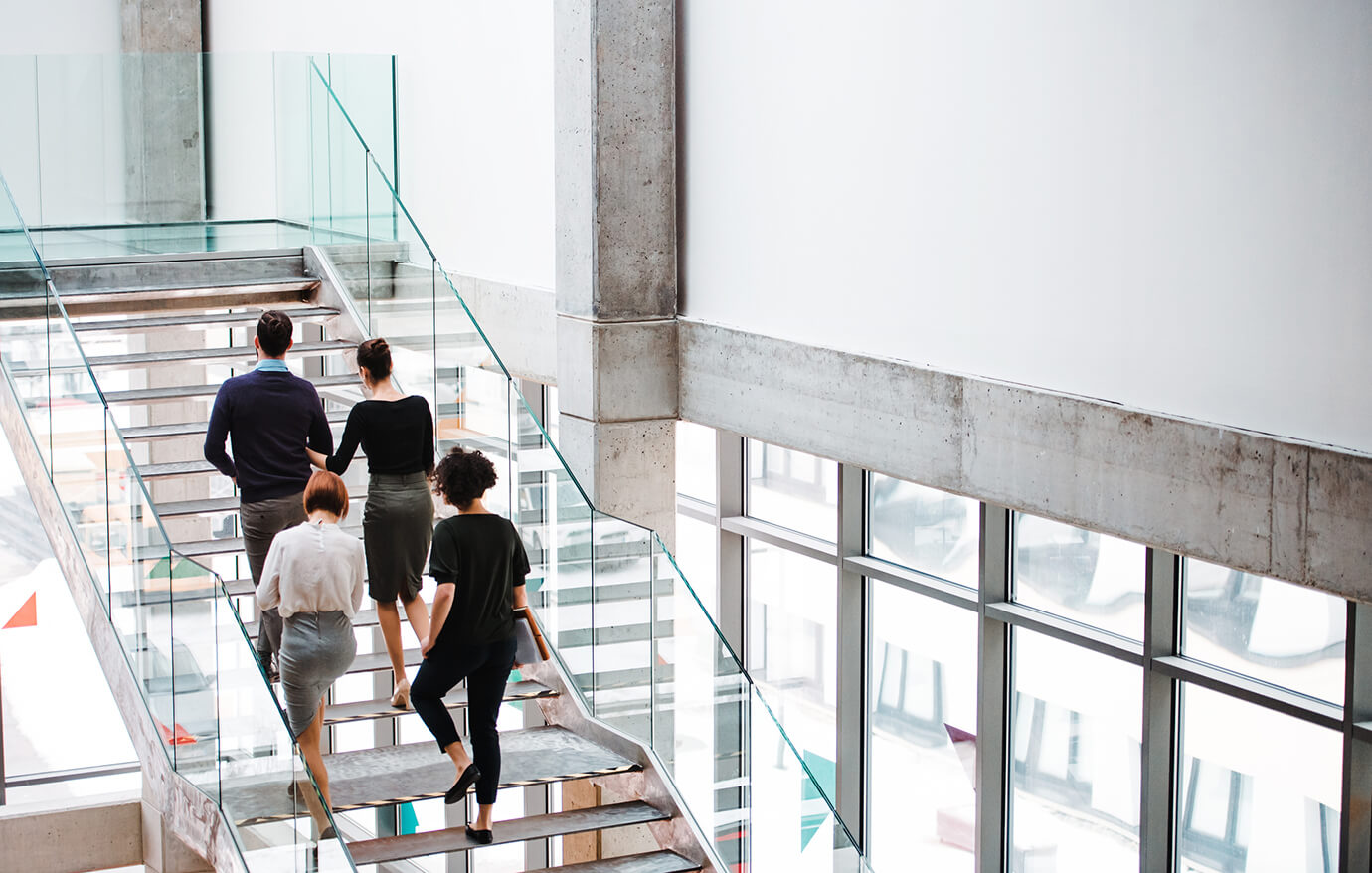 Transactions A group of office workers walking up a glass staircase