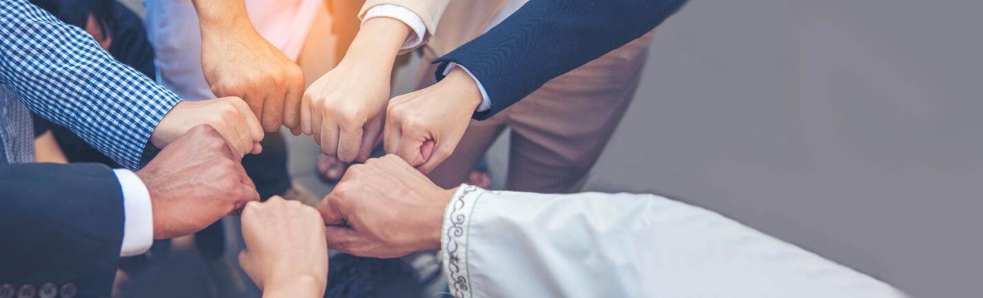 Group of people putting their closed fists into a circle