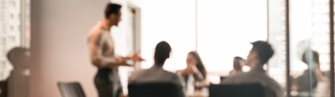 Blurred image of a man talking to a group in a meeting